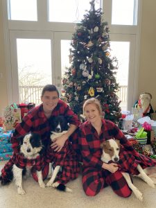 Photo of Jon Emerson sitting in front of a Christmas tree with a woman and two dogs