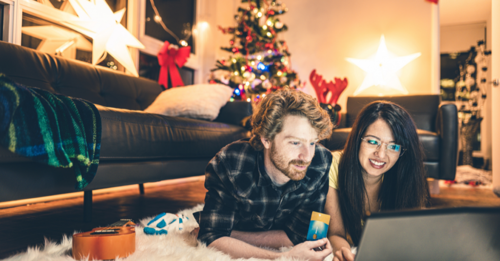 Picture of a man and a woman looking at a laptop computer in front of a Christmas tree