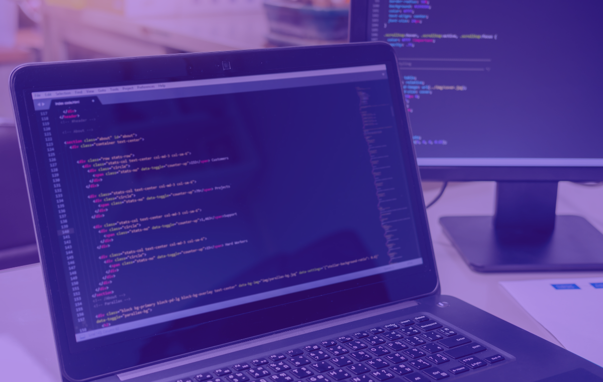A laptop and desktop monitor showing website code
